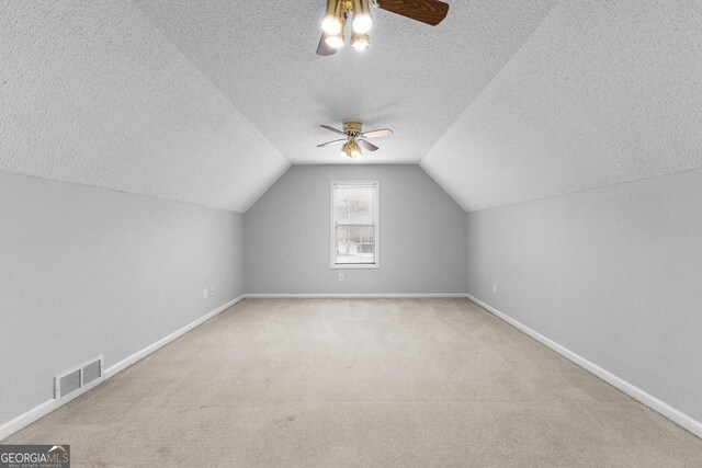 bonus room featuring ceiling fan, vaulted ceiling, carpet, and a textured ceiling