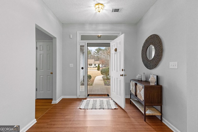 foyer entrance with wood-type flooring and a textured ceiling