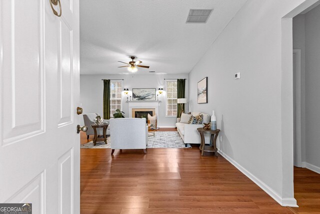 living room featuring independent washer and dryer, ceiling fan with notable chandelier, a textured ceiling, and light wood-type flooring