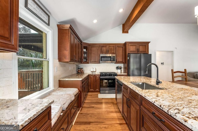 kitchen with sink, light wood-type flooring, tasteful backsplash, and appliances with stainless steel finishes