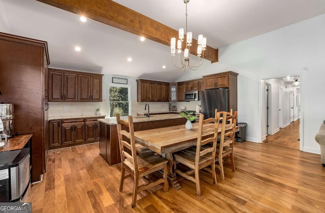 dining area featuring sink, a chandelier, light wood-type flooring, high vaulted ceiling, and beam ceiling