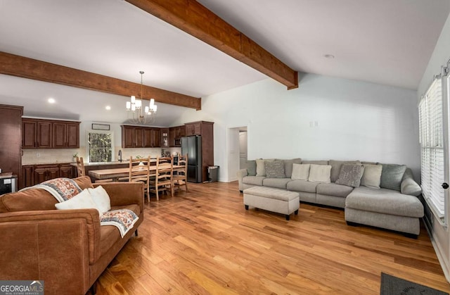 living room with light wood-type flooring, an inviting chandelier, and lofted ceiling with beams