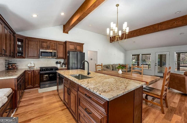 kitchen with black appliances, light hardwood / wood-style flooring, sink, lofted ceiling with beams, and a center island with sink