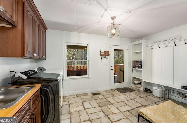 clothes washing area with cabinets, washer and clothes dryer, and sink