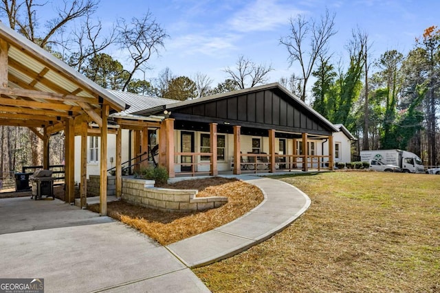 rear view of house featuring a lawn and a porch