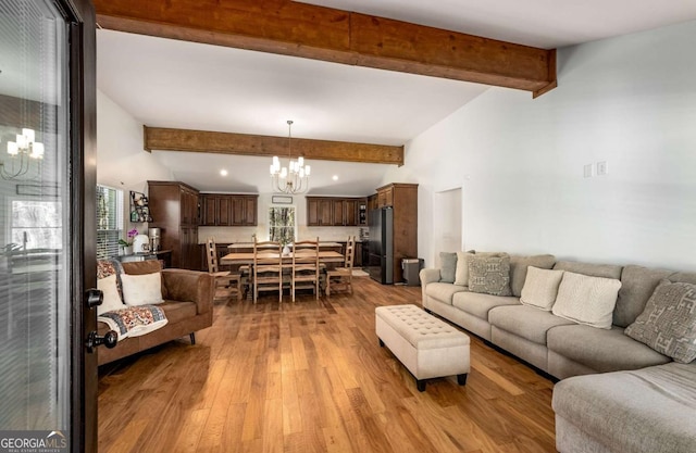 living room featuring light wood-type flooring, beamed ceiling, and a notable chandelier