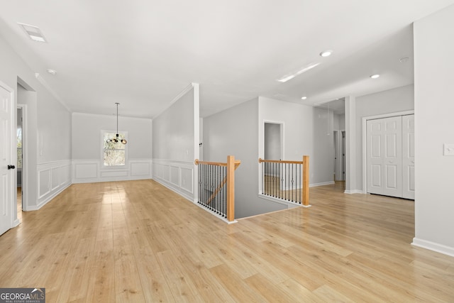 empty room featuring light hardwood / wood-style floors, a notable chandelier, and ornamental molding