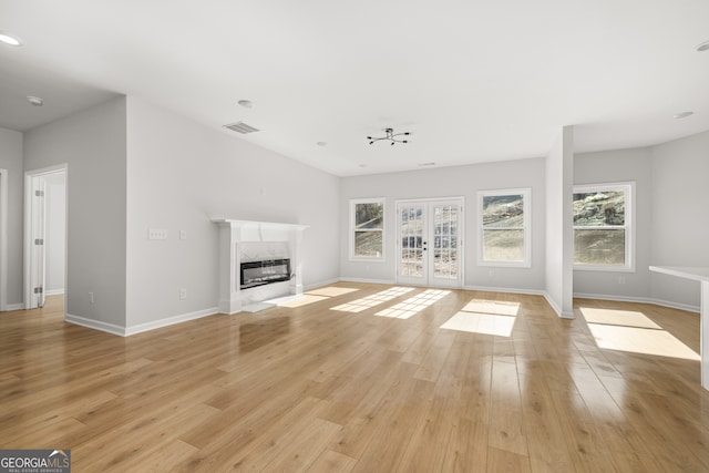 unfurnished living room featuring french doors, light hardwood / wood-style flooring, and a premium fireplace