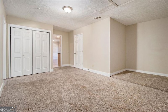 unfurnished bedroom with a textured ceiling, a closet, and carpet flooring