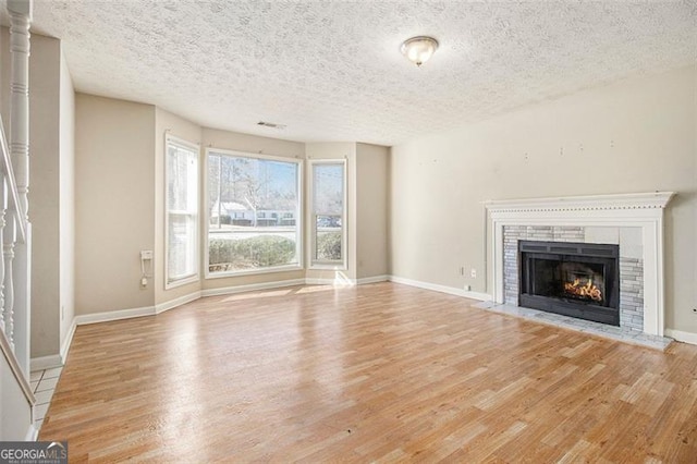 unfurnished living room with light wood-type flooring and a textured ceiling