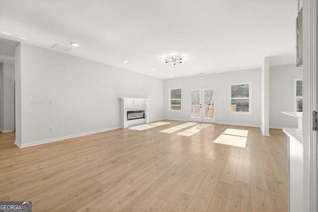 unfurnished living room featuring french doors and light hardwood / wood-style flooring