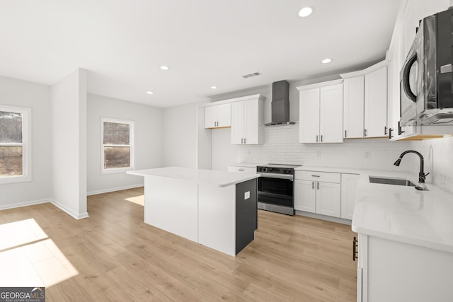 kitchen with a kitchen island, wall chimney range hood, white cabinetry, sink, and electric range