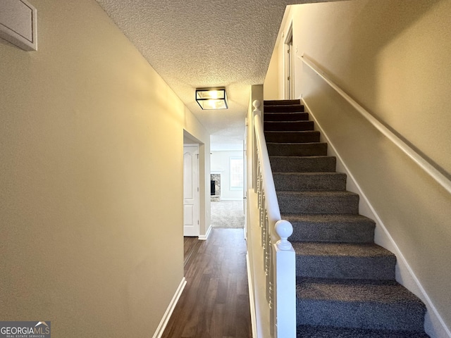 stairs featuring wood-type flooring and a textured ceiling