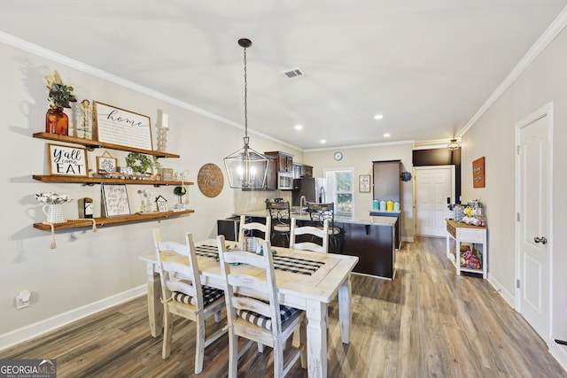 dining area featuring crown molding and light hardwood / wood-style floors