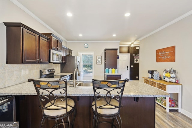 kitchen featuring light stone countertops, a kitchen breakfast bar, appliances with stainless steel finishes, and a kitchen island