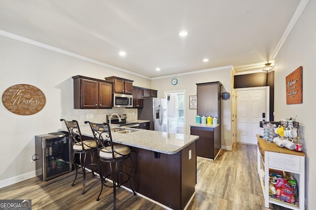 kitchen featuring kitchen peninsula, light stone counters, ornamental molding, light hardwood / wood-style floors, and stainless steel appliances