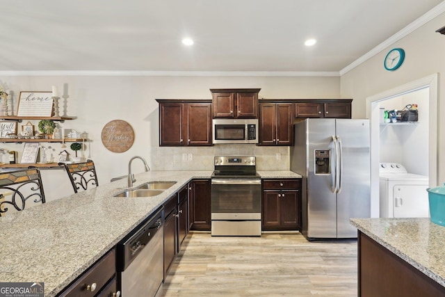 kitchen featuring washer and clothes dryer, appliances with stainless steel finishes, sink, backsplash, and light stone counters