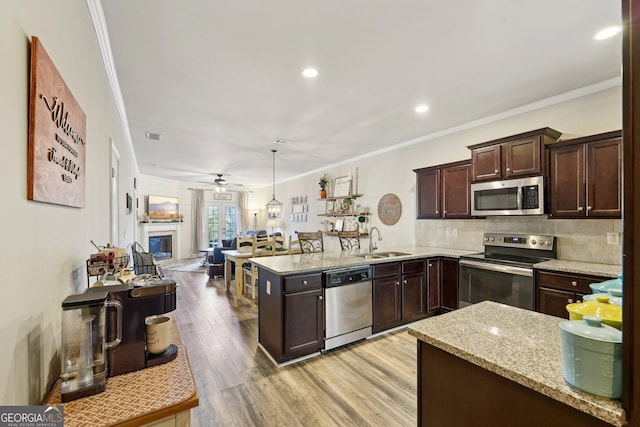 kitchen featuring sink, ornamental molding, appliances with stainless steel finishes, and pendant lighting