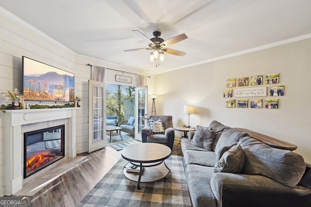 living room featuring ceiling fan, ornamental molding, and light wood-type flooring