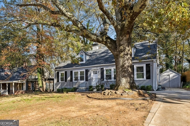 cape cod home with a front yard and a shed