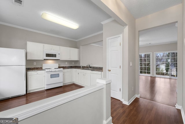 kitchen with visible vents, white appliances, dark countertops, and white cabinetry