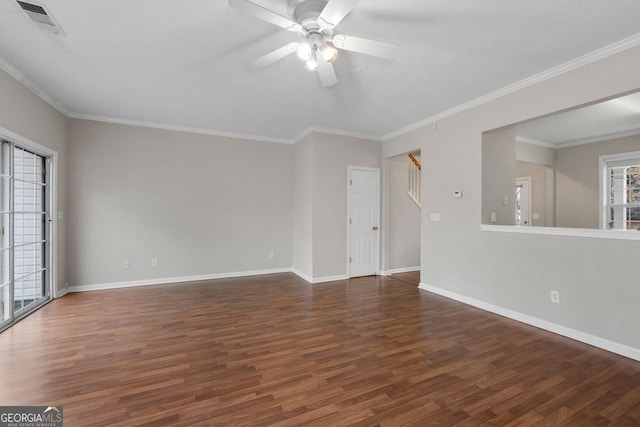 empty room with dark wood-style flooring, a ceiling fan, visible vents, baseboards, and ornamental molding