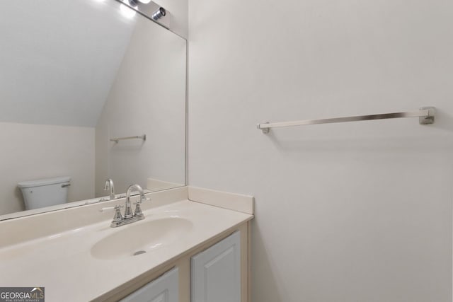 bathroom with vaulted ceiling, vanity, and toilet