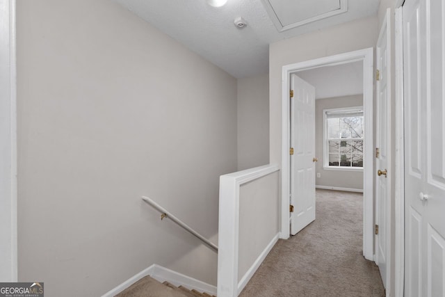 hall with baseboards, an upstairs landing, and light colored carpet