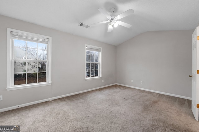 spare room with baseboards, visible vents, a ceiling fan, vaulted ceiling, and carpet flooring