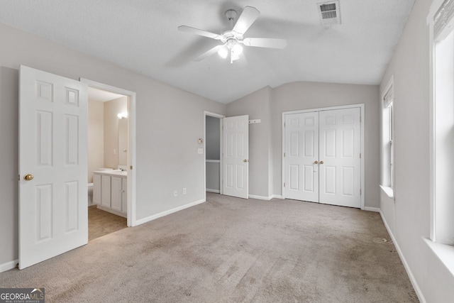 unfurnished bedroom with light carpet, baseboards, visible vents, lofted ceiling, and a closet