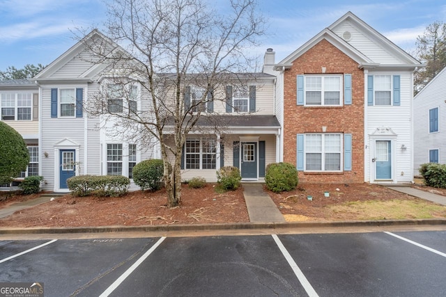 multi unit property featuring uncovered parking, brick siding, and a chimney