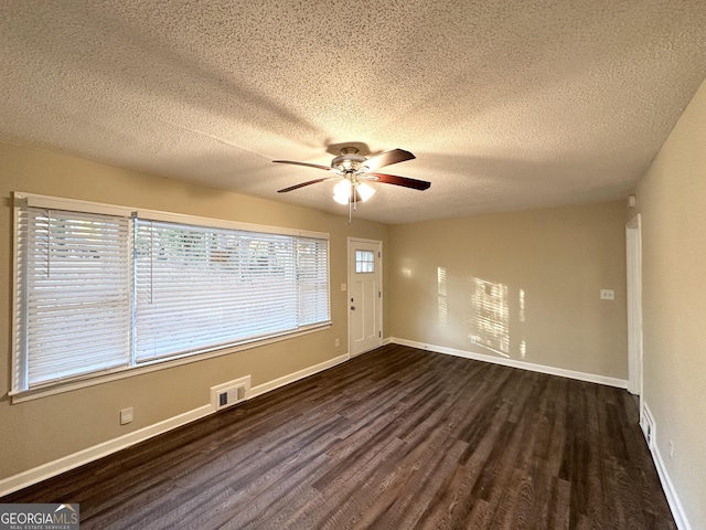 empty room with a textured ceiling, dark hardwood / wood-style floors, and ceiling fan