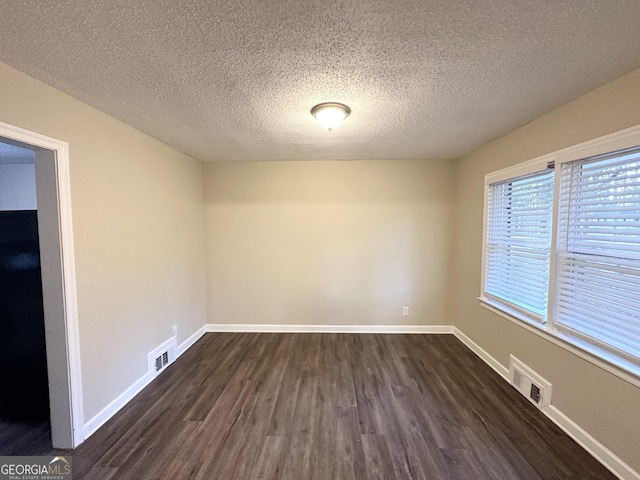 unfurnished room with dark wood-type flooring and a textured ceiling