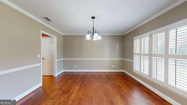 spare room featuring dark wood-type flooring, a chandelier, and ornamental molding