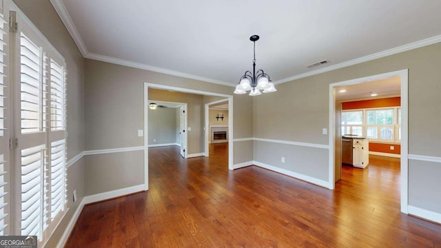 unfurnished dining area featuring hardwood / wood-style floors, ornamental molding, and a notable chandelier