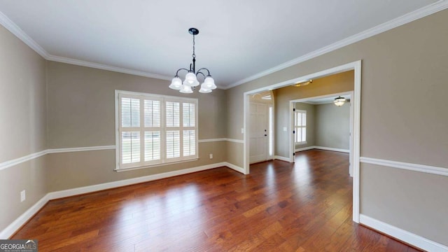 unfurnished room with dark wood-type flooring, ornamental molding, and an inviting chandelier