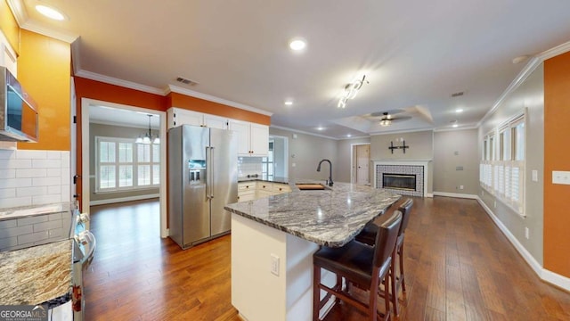 kitchen with appliances with stainless steel finishes, decorative backsplash, white cabinets, sink, and a breakfast bar