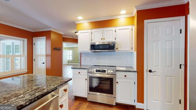 kitchen featuring appliances with stainless steel finishes, light wood-type flooring, white cabinets, dark stone countertops, and decorative backsplash