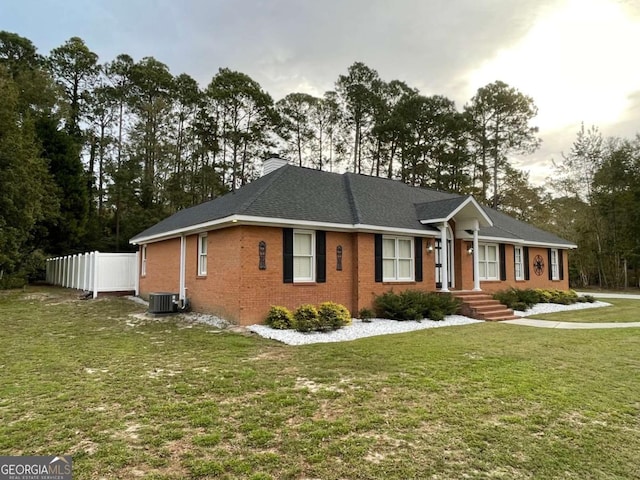 ranch-style house featuring a front yard and central AC unit