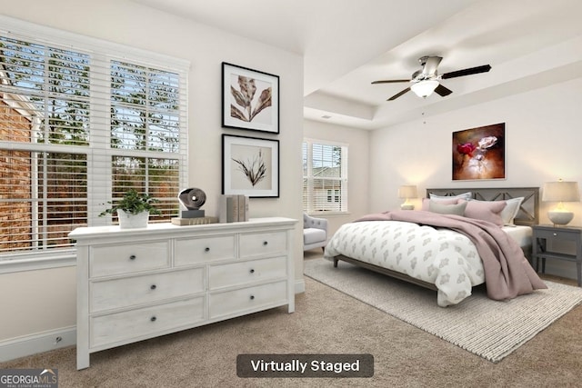 bedroom featuring light colored carpet, ceiling fan, and a raised ceiling