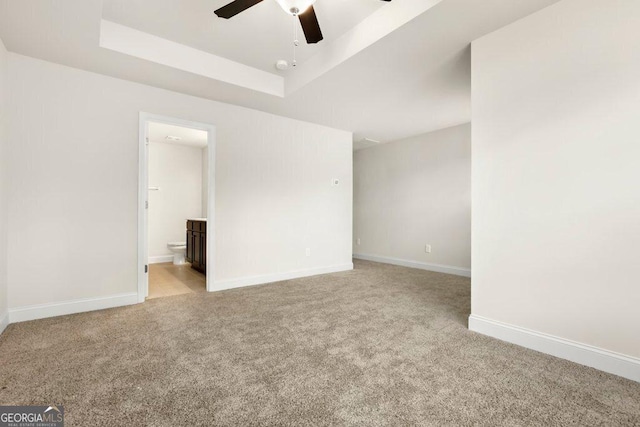 carpeted empty room with ceiling fan and a raised ceiling