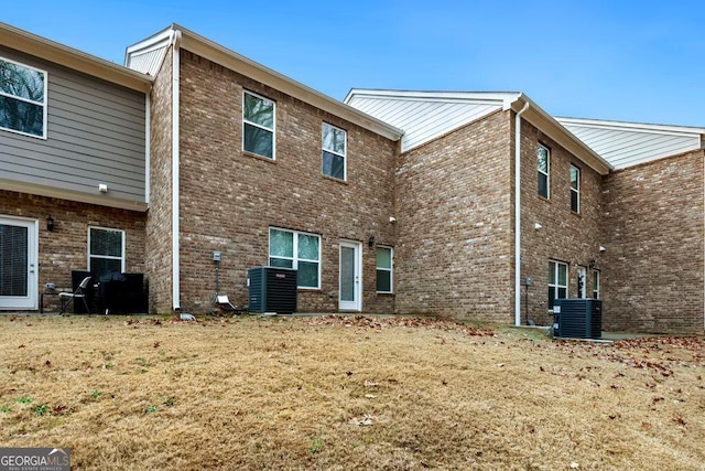 rear view of house with a lawn and central AC