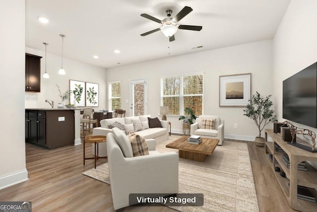 living room with sink, ceiling fan, and light hardwood / wood-style floors