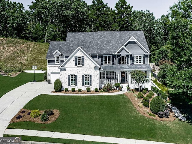 view of front of property featuring covered porch, a front yard, and a garage