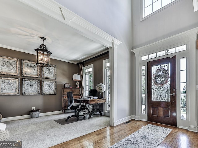 foyer entrance featuring wood-type flooring, crown molding, and an inviting chandelier