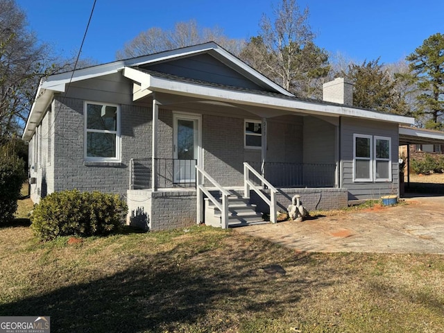 bungalow featuring covered porch and a front yard