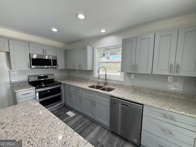 kitchen with light stone countertops, sink, appliances with stainless steel finishes, and gray cabinetry