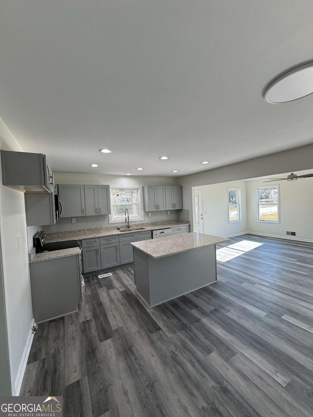 kitchen featuring gray cabinetry, a center island, stove, and plenty of natural light