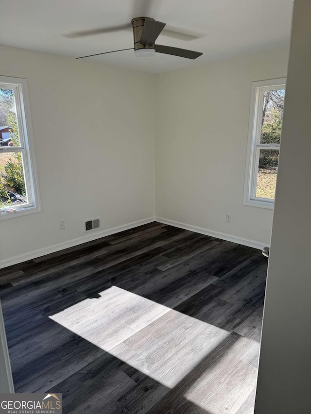 empty room with ceiling fan, a wealth of natural light, and dark hardwood / wood-style flooring