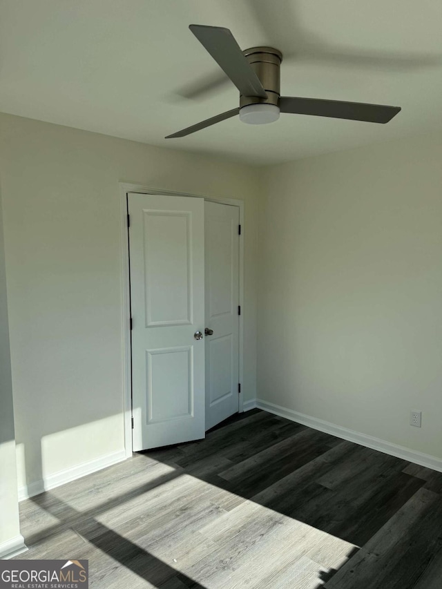 unfurnished bedroom with ceiling fan, a closet, and dark hardwood / wood-style flooring